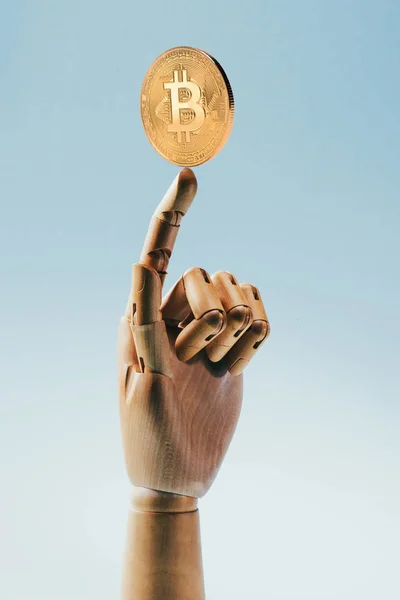 Close up view of wooden puppet hand holding golden bitcoin isolated on blue — Stock Photo