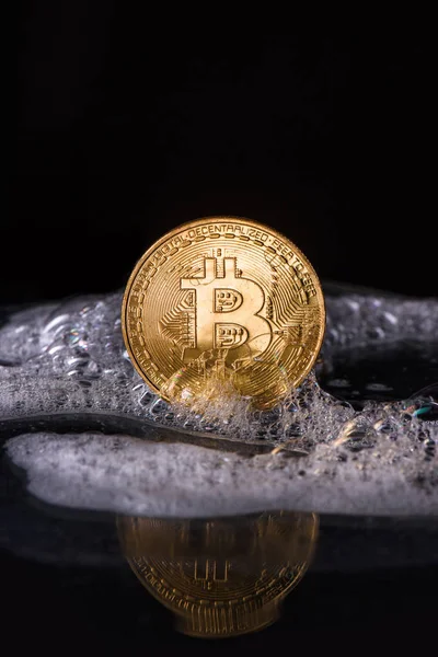 Close up view of golden bitcoin in soap isolated on black — Stock Photo