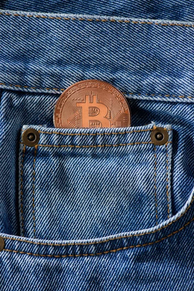 Крупный план бронзового биткойна в джинсовом кармане — стоковое фото