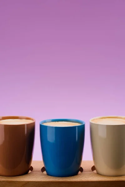 Nahaufnahme der bunten Tassen Kaffee isoliert auf lila — Stockfoto