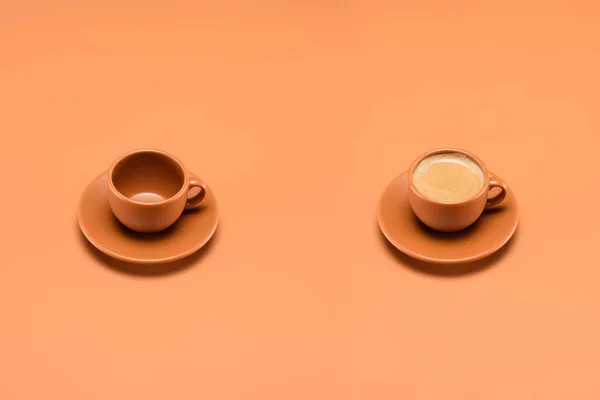 Close up view of empty cup and cup of coffee isolated on peach — Stock Photo