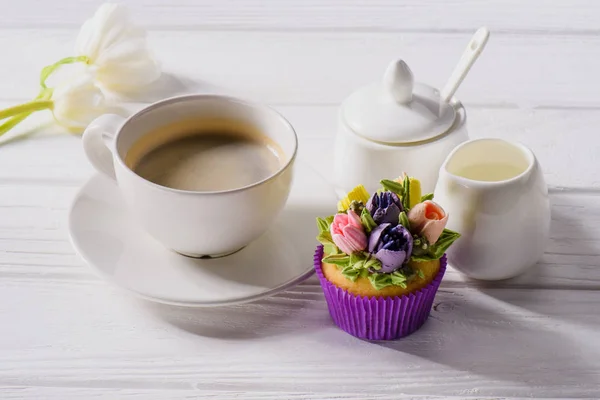 Vue rapprochée des tulipes, tasse de café, muffin sucré et jag de crème sur table en bois blanc — Photo de stock