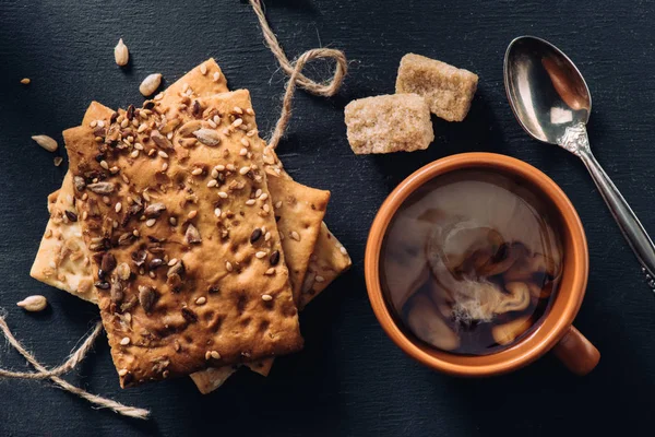 Top view of cookies, cup of coffee, spoon and brown sugar on dark tabletop — Stock Photo