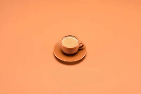 Close up view of cup of coffee on saucer isolated on peach — Stock Photo