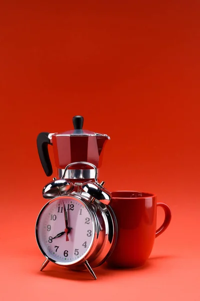 Vista de cerca de la cafetera, despertador y taza de café aislado en rojo - foto de stock