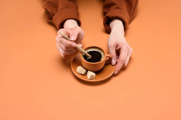 Abgeschnittene Aufnahme weiblicher Hände mit Tasse Kaffee und Bleistift isoliert auf Pfirsich — Stockfoto