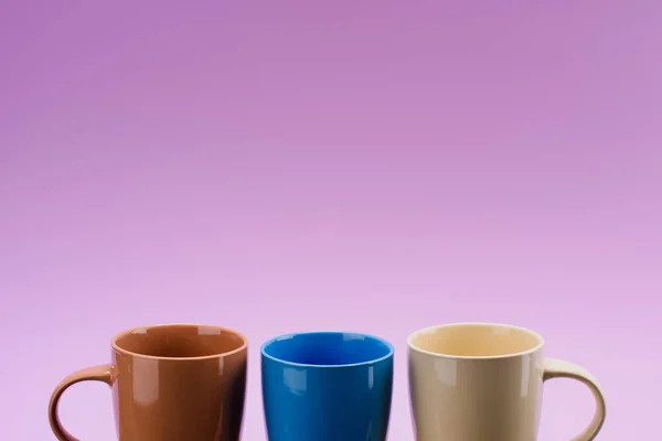 Close up view of arrangement of empty cups isolated on purple — Stock Photo