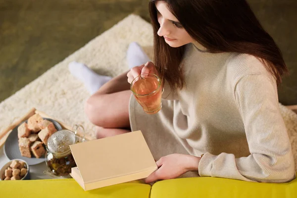 Frau mit Tasse Tee und Buch zu Hause aus der Vogelperspektive — Stockfoto