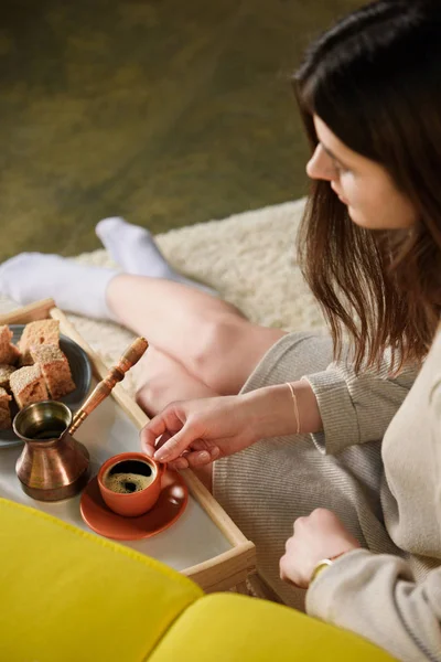 Selektiver Fokus der jungen Frau mit Tasse Kaffee auf Holztablett zu Hause — Stockfoto