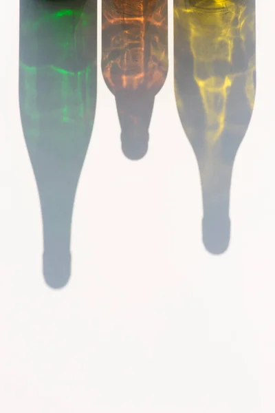 Vista de perto de garrafas coloridas sombras na superfície branca — Fotografia de Stock