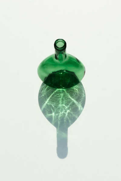 Vue rapprochée de la bouteille en verre vide avec réflexion sur la table blanche — Photo de stock