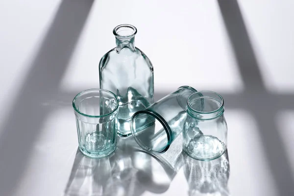 Bouteille de vue rapprochée avec de l'eau et des verres vides sur la table blanche — Photo de stock