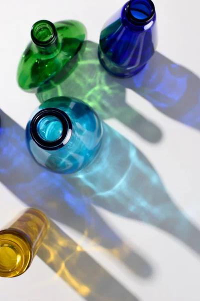 Vista superior de garrafas de vidro coloridas vazias na superfície branca — Fotografia de Stock