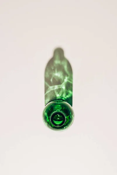 Vista superior da garrafa de vidro verde vazio com sombra na mesa branca — Fotografia de Stock