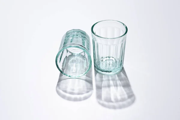 Nahaufnahme leerer Gläser und Schatten auf weißer Oberfläche — Stockfoto