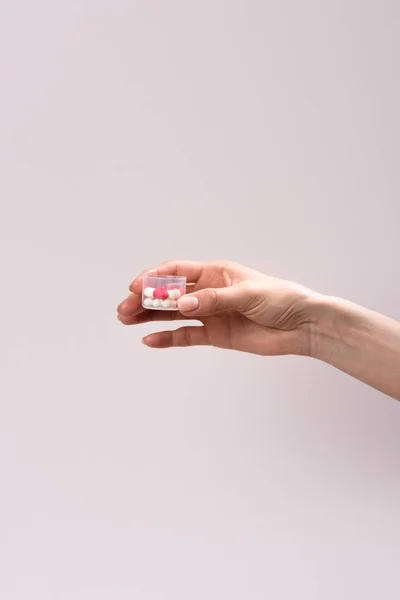 Tiro recortado de mulher segurando recipiente de plástico de pílulas isoladas em cinza — Fotografia de Stock