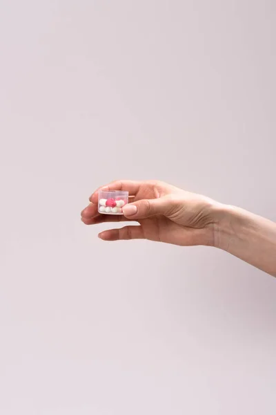 Cropped shot of woman holding plastic container of pills isolated on grey — Stock Photo