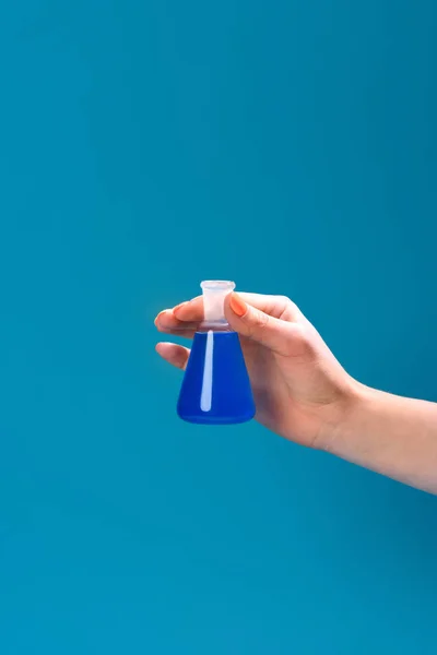 Tiro recortado de mulher segurando frasco de líquido azul isolado em azul — Fotografia de Stock