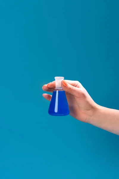 Colpo ritagliato di donna che tiene in mano fiaschetta di liquido blu isolato su blu — Foto stock