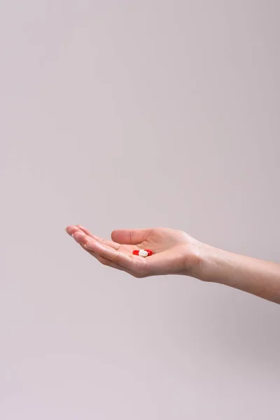 Tiro cortado de mulher segurando montão de pílulas na mão isolado em cinza — Fotografia de Stock