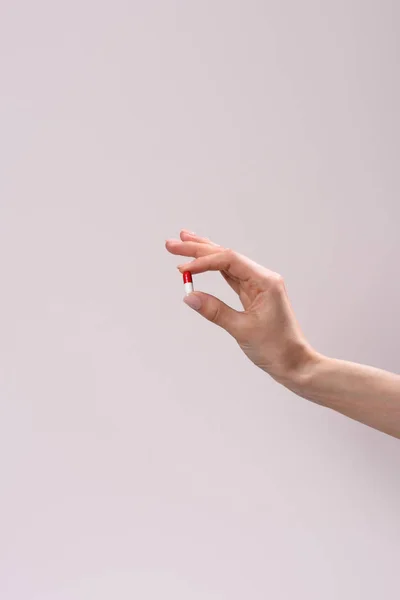 Cropped shot of woman holding drug capsule isolated on grey — Stock Photo