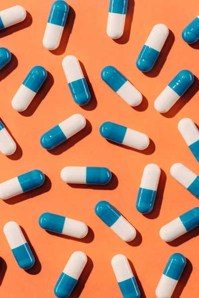 Top view of blue and white pills on orange surface — Stock Photo