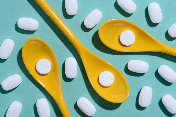 Top view of white pills in plastic spoons on blue surface — Stock Photo