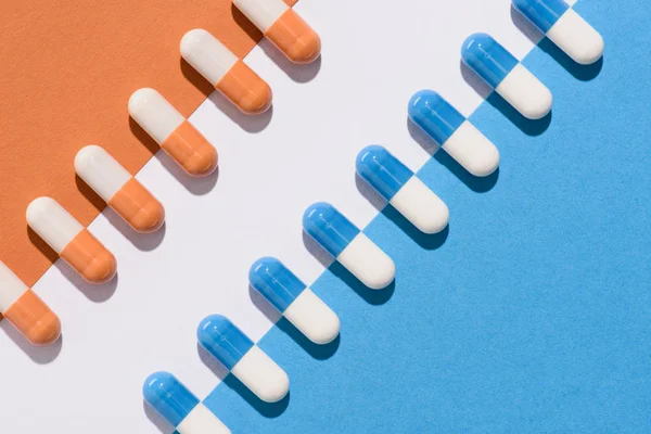Vista dall'alto di pillole blu e arancioni sulla superficie colorata — Foto stock