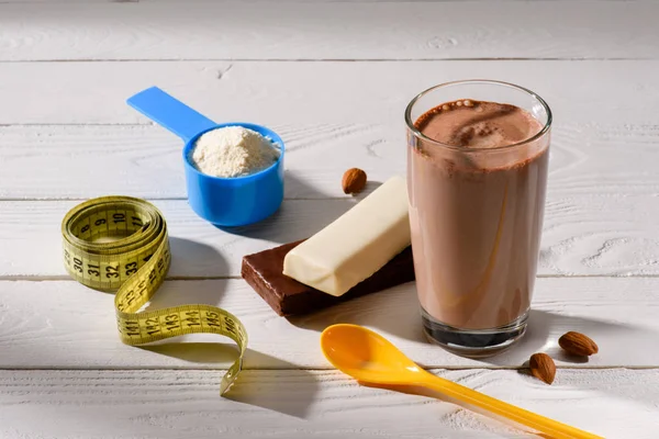 Gros plan de la nutrition sportive et du ruban à mesurer sur une table en bois blanc — Photo de stock