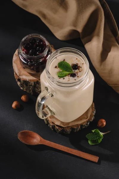 Closeup view of milkshake, mint, currants, walnuts, spoon, kitchen towel and wooden slices — Stock Photo