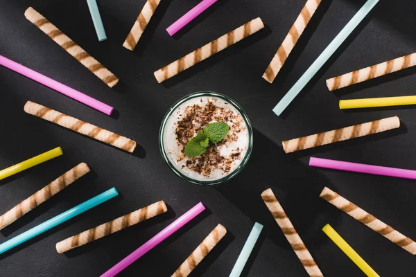 Top view of milkshake with chocolate shavings and mint surrounded by sweet and drinking straws — Stock Photo