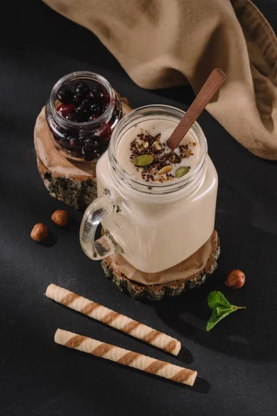 Closeup view of milkshake with chocolate shavings and pistachio nuts, currants, walnuts, mint and sweet straws — Stock Photo