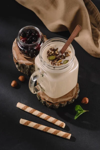 Vista de cerca del batido con virutas de chocolate y pistachos, grosellas, nueces, menta y pajitas dulces - foto de stock