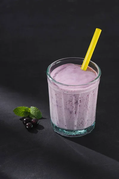 Closeup shot of berry smoothie glass with drinking straw, currants and mint on table — Stock Photo