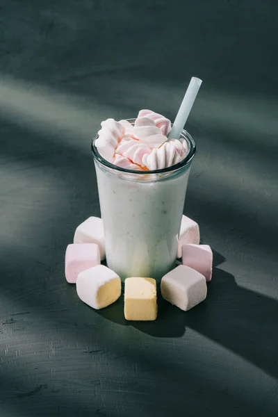 Closeup shot of marshmallows, milkshake glass with drinking straw on table — Stock Photo