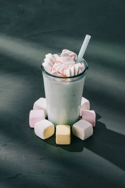 Primer plano de malvaviscos, vaso de batido con paja para beber en la mesa - foto de stock