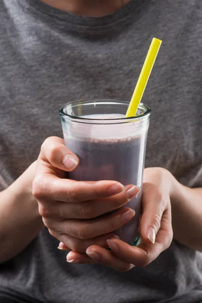 Cropped image of woman holding berry smoothie glass with drinking straw — Stock Photo