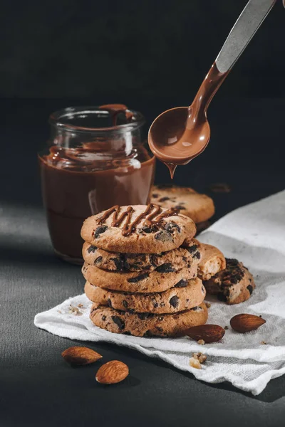 Close-up shot of liquid chocolate pouring onto stacked chocolate-chip cookies — Stock Photo