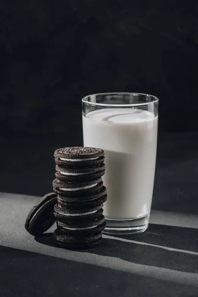 Deliziosi biscotti sandwich con vetro di latte sulla superficie nera — Foto stock