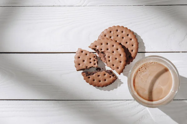 Top view of cracked cookies with glass of cocoa on wooden table — Stock Photo