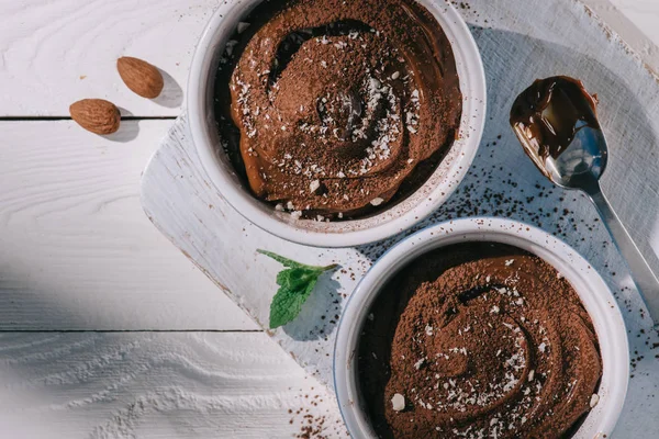 Top view of bowls with chocolate dessert on wooden board on table — Stock Photo