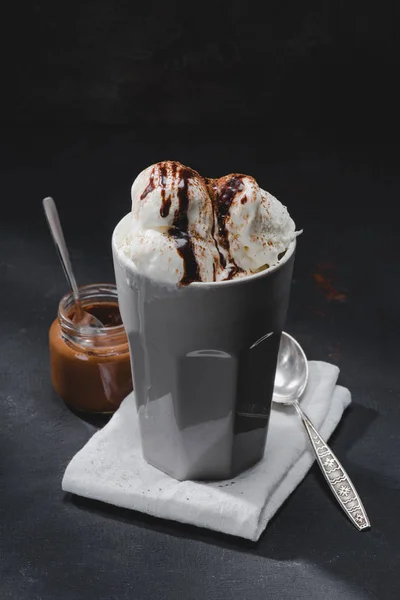 Delicioso helado en taza y frasco con chocolate en la mesa - foto de stock