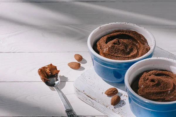 Ciotole con gustoso dessert al cioccolato con cacao in polvere su tavolo di legno — Foto stock