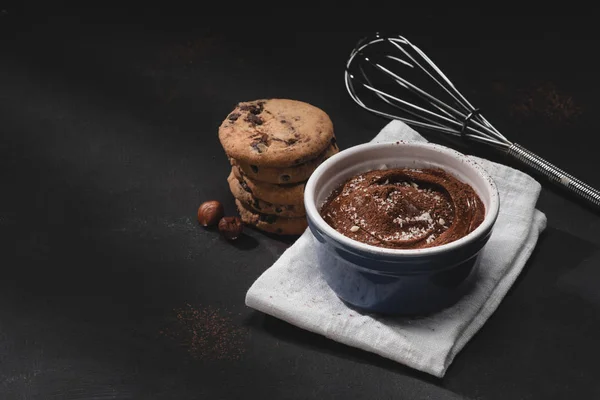 Schüssel mit Schokoladendessert, Schneebesen und Keksen auf der Tischplatte — Stockfoto