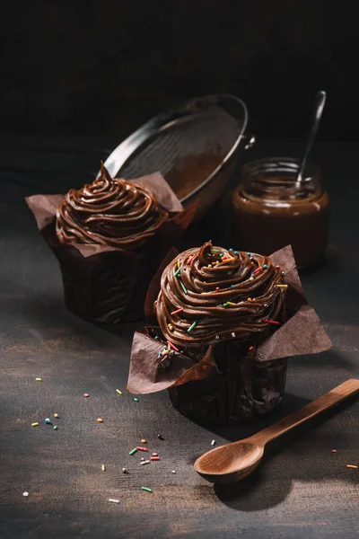 Leckere Schokolade gekochte Cupcakes und Sieb auf dem Tisch — Stockfoto