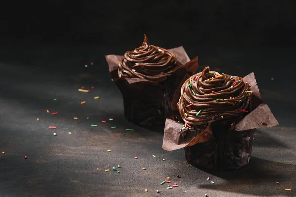 Gâteaux au chocolat délicieux avec glaçage à la crème au beurre et tartinade de sucre sur la table — Photo de stock