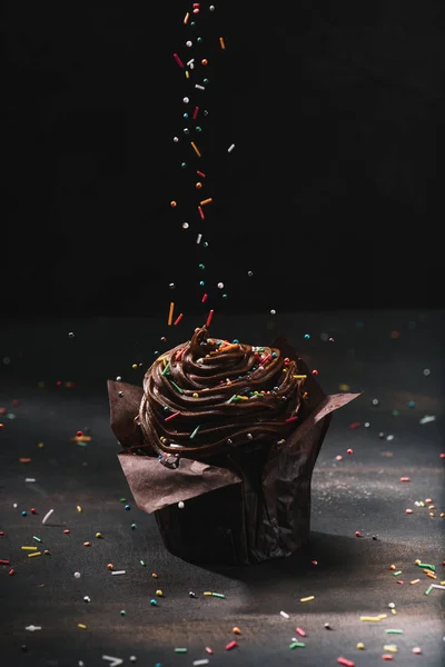 Tasty chocolate cupcake with glaze and sugar spreading on table — Stock Photo