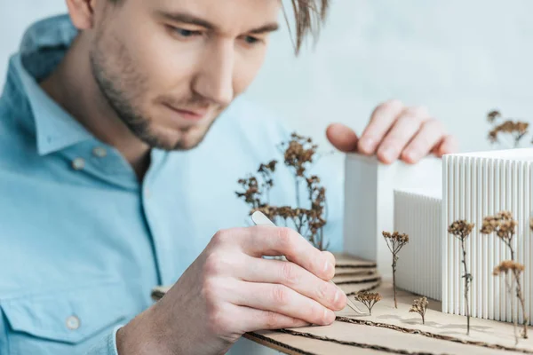 Foco seletivo do arquiteto focado olhando para o modelo de construção auto-feita no escritório — Fotografia de Stock