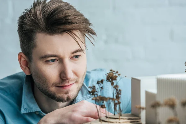 Enfoque selectivo del arquitecto mirando el modelo de edificio hecho a sí mismo en la oficina - foto de stock