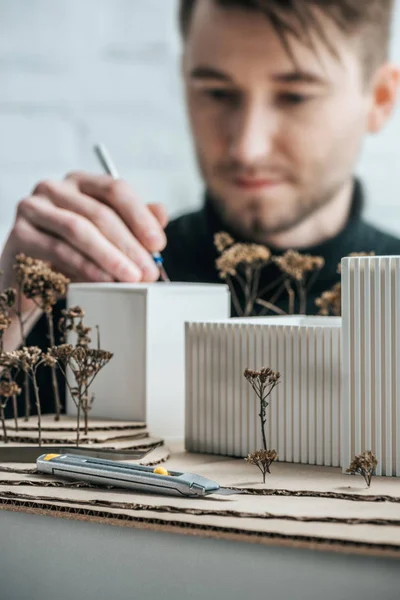 Селективный фокус архитектора раскраски самодельной строительной миниатюры с кистью в офисе — стоковое фото